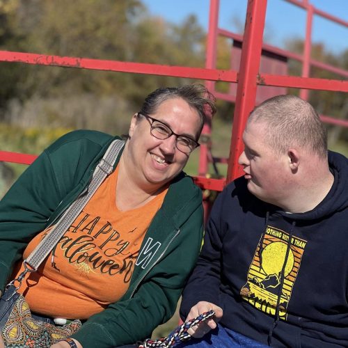 A teacher poses with her student, a young man with Down Syndrome.